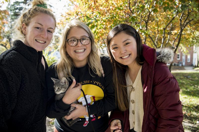 3 students smiling with trees in the background.